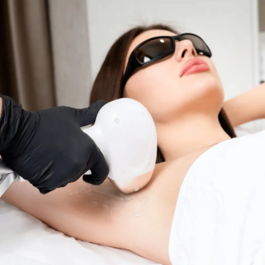 Underarm laser hair removal treatment using handheld medical laser device while patient wears protective glasses during session.