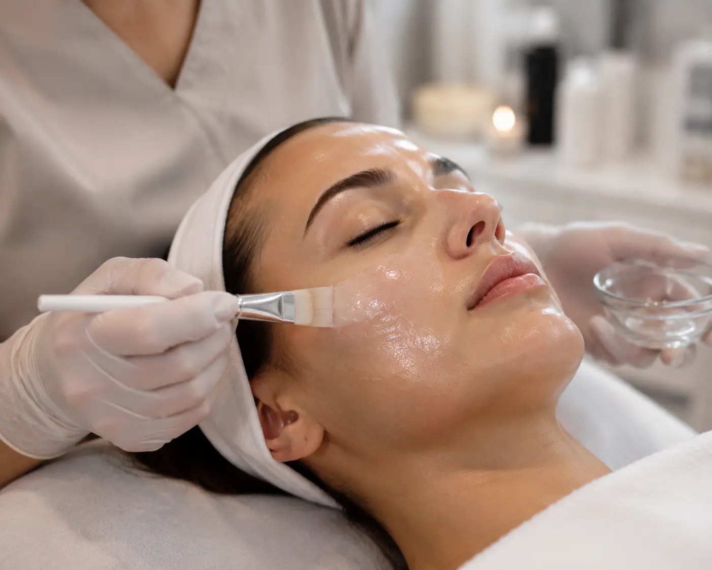 Close-up of an Arizona MedLaser aesthetician applying a hydrating facial mask or serum to a client’s face using a brush during a professional spa treatment.