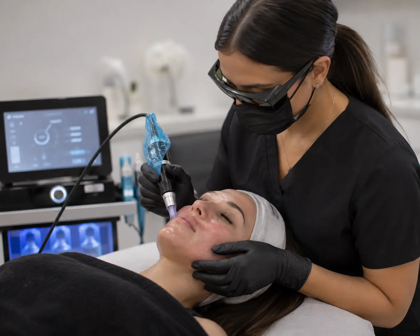 Arizona MedLaser aesthetician performing microneedling treatment on a client’s face using a professional device, while the client relaxes with eyes closed and protective headband.